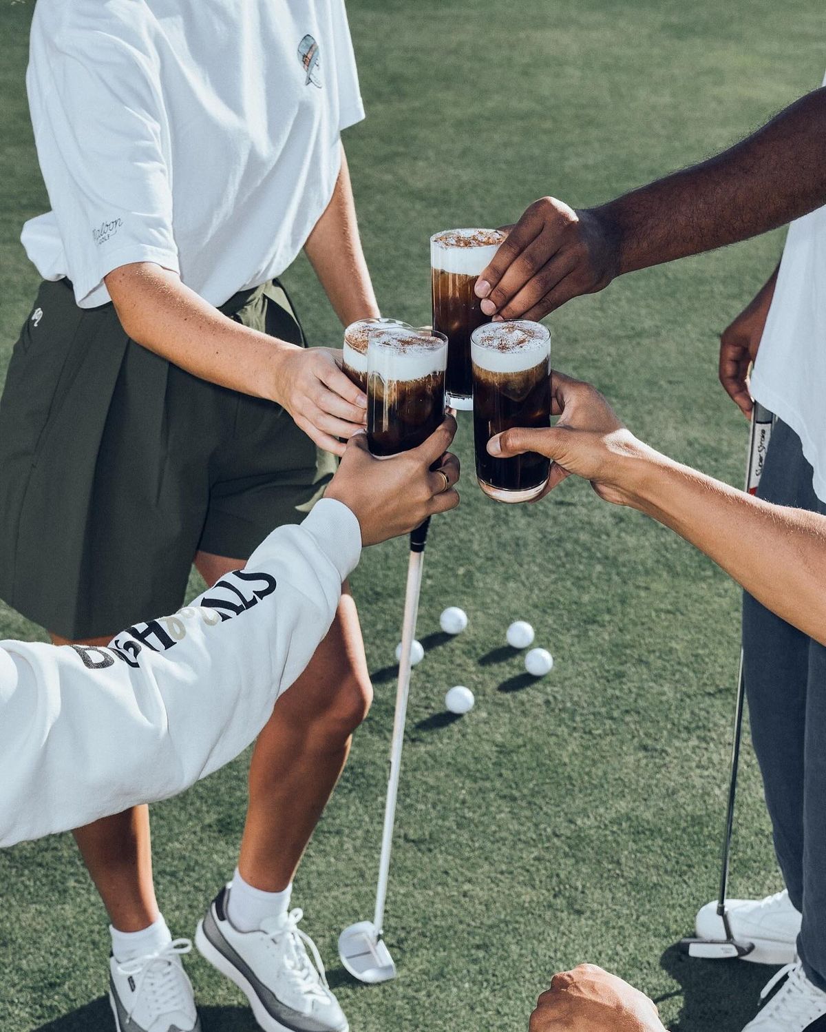 Friends toasting iced drinks over golf balls at a Golf Anywhere event